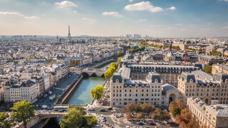 Stunning aerial shot, Paris cityscape, Seine River, clear blue skies overhead. 