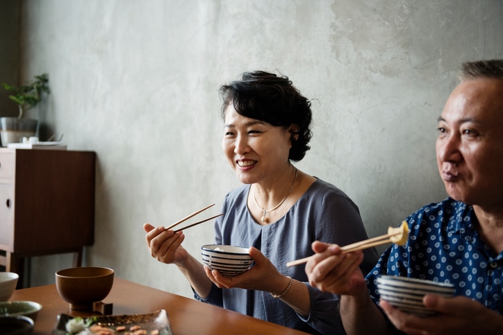 Mature couple eating with chop sticks in Kyoto, Japan.
