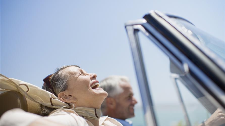Mature couple enjoying a road trip drive with the top down. 