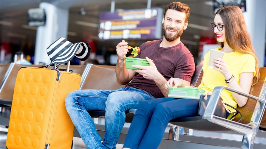 Young couple eating at an airport on a layover. 