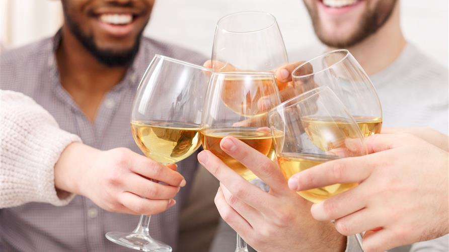 Friends celebrating missed milestones and toasting wine while smiling. 