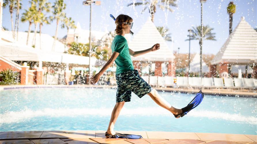 Young boy playing poolside in flippers and goggles at Hilton Grand Vacations at SeaWorld resort in Orlando, Florida. 