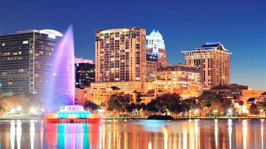 Lake Eola fountain and Orlando skyline lit up at night. 