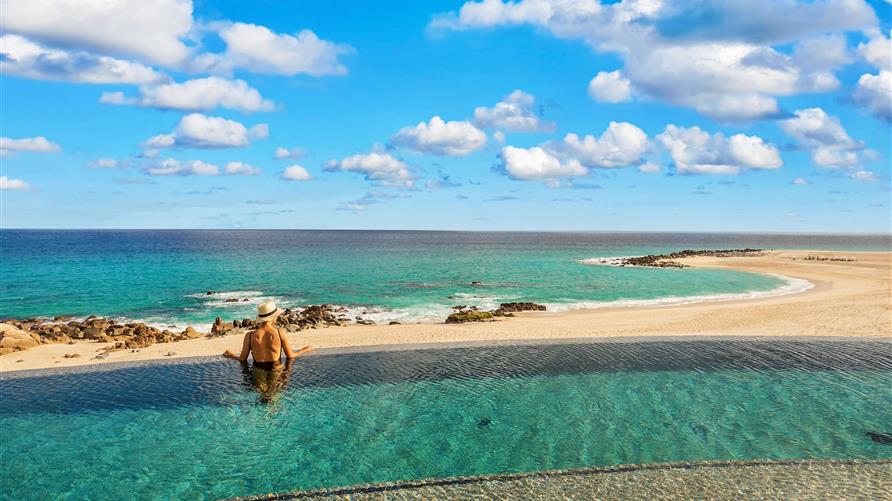 Woman gazing into the Sea of Cortez from the infinity pool at La Pacifica by Hilton Club in Los Cabos, Mexico. 