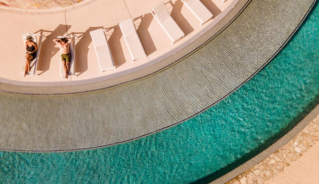 Couple lounging poolside at La Pacifica by Hilton Club in Los Cabos, Mexico. 