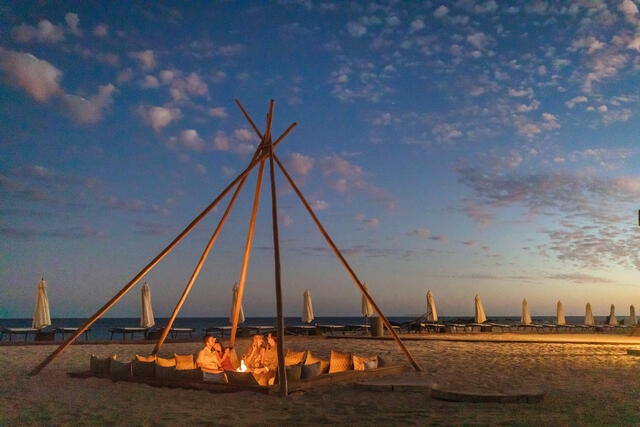 Group of friends enjoying fire pit on the beach at La Pacifica Los Cabos by Hilton Club in Mexico.