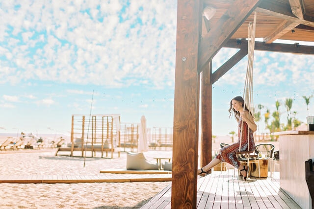Woman happily swinging on a beach side swing at La Pacifica Los Cabos by Hilton Club, Mexico. 