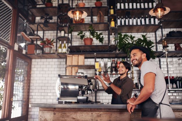 Shot of two coffee shop workers smiling and making coffee.