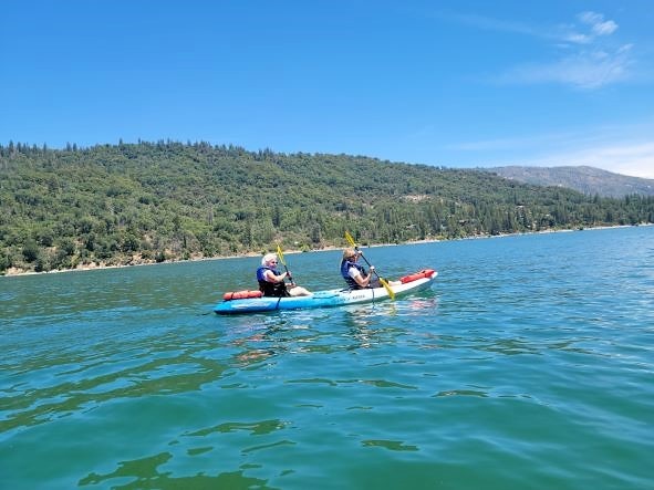 Hilton Grand Vacations Owners kayaking, mountains in the distance, blue skies overhead. 