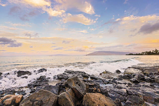 Waves crashing against lava rock, cotton candy skies overhead, Maui, Hawaii. 