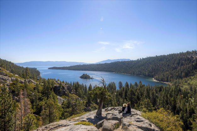 A couple sits on a rock overlooking Lake Tahoe in California