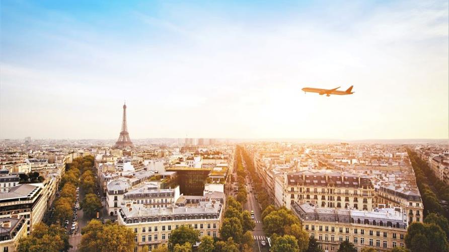 An airplane over the Paris skyline and Eiffel Tower at sunrise