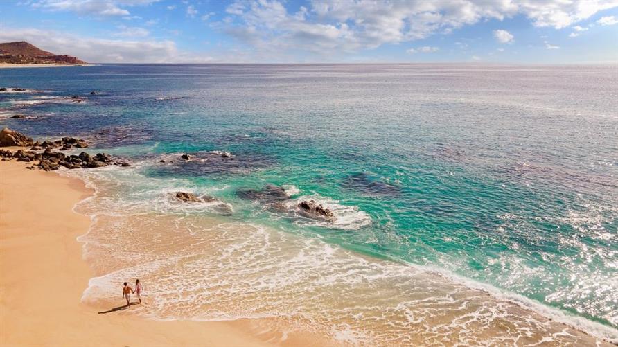 An aerial view of a couple on the beach of Los Cabos, Mexico