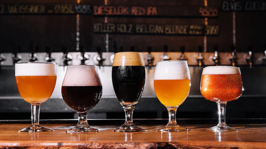 Different types of craft beer in glasses on table in brewery