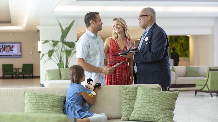 A husband and wife speak to an HGV Club Counselor while standing in a resort lobby
