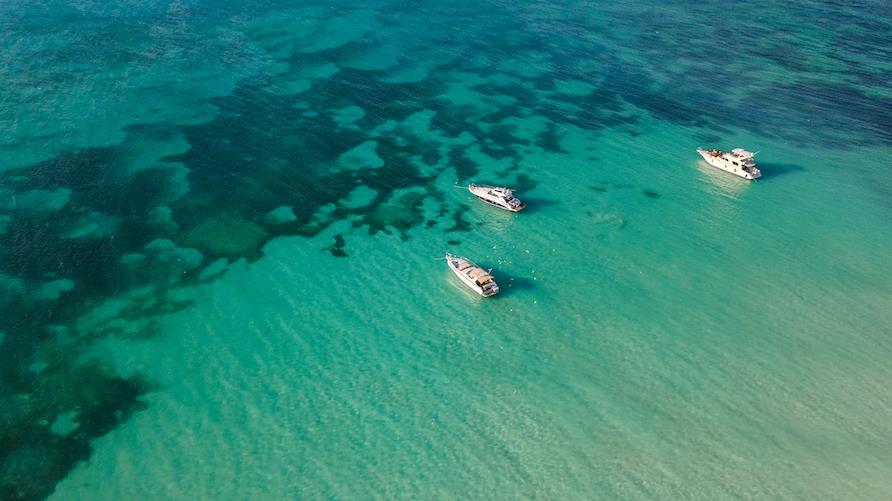 Gorgeous aerial view of three luxury yachts anchored on the transparent and turquoise waters of the Caribbean