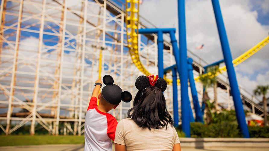 A mother and her young son look towards a large roller coaster at a theme park in Orlando, Florida