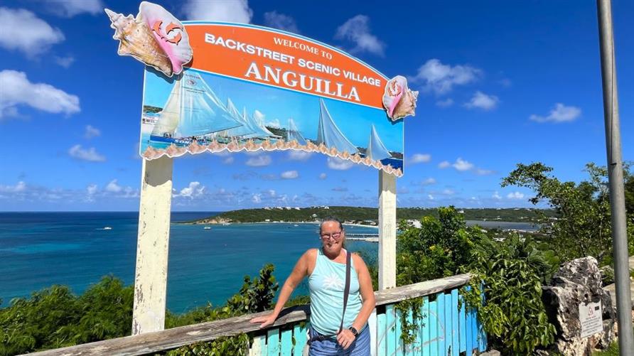 A Hilton Grand Vacations Member posing by a sign for Anguilla