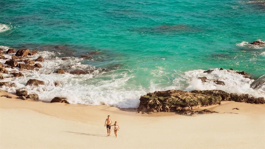 Aerial view of two people holding hands on the beach near La Pacifica Los Cabos, a Hilton Club in Mexico