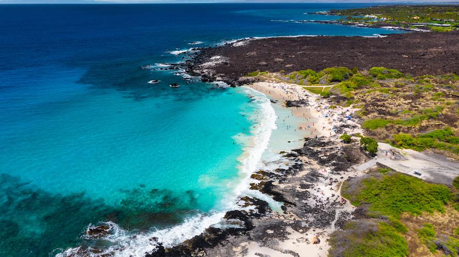 Beautiful aerial view of the turquoise reef, crystal-clear water, coastal lava rocks and white sand beach at Kua Bay, Big Island, Hawaii