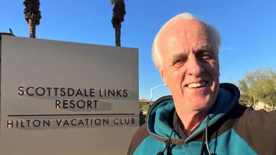 A Hilton Grand Vacations Member next to a sign for  Scottsdale Links Resort, a Hilton Vacation Club in Arizona