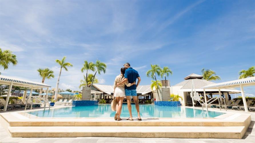 A couple stands together at the pool at Royal Palm, a Hilton Vacation Club in Sint Maarten in the Caribbean