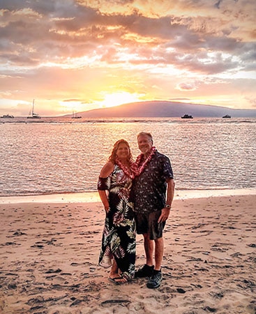 Hilton Grand Vacations Member Maria N. and her partner Mark posing on the beach at sunset