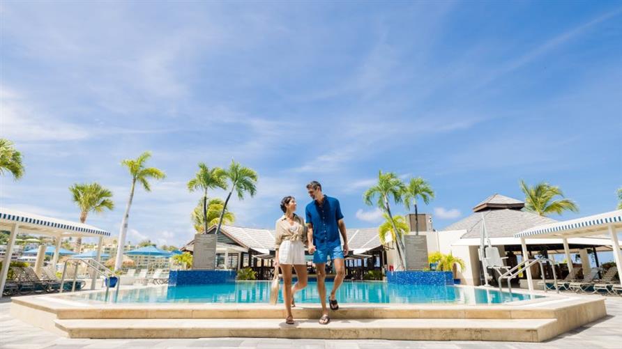 A couple holds hands by the pool of Royal Palm, a Hilton Vacation Club in Sint Maarten, Netherlands Antilles