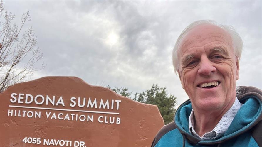 A Hilton Grand Vacations Member taking a selfie outside of Sedona Summit, a Hilton Vacation Club