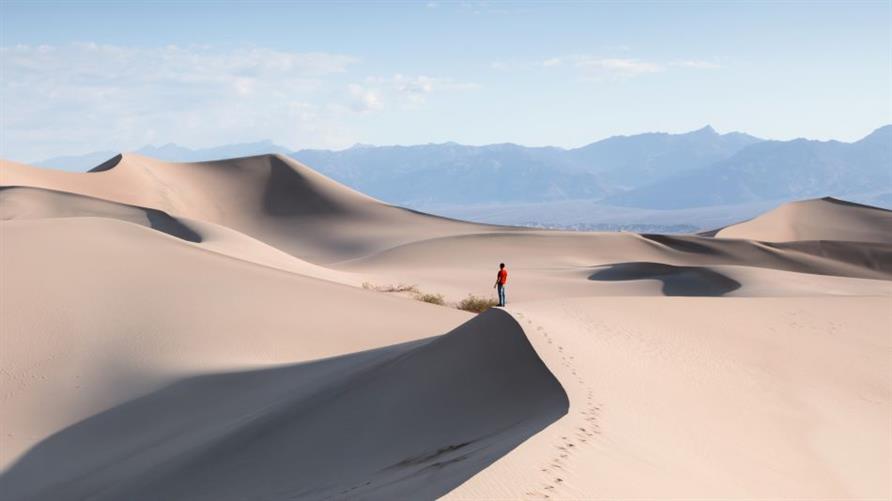 Person  in red coat standing amid Mesquite Flat Sand Dunes in Death Valley National Park in California