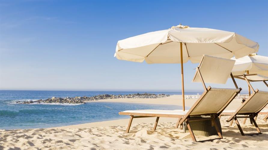 Two beach chairs and an umbrella on a beach on a sunny day