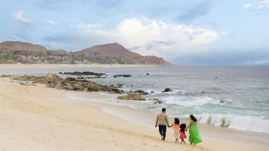 A family walks on the beach near La Pacifica Los Cabos, a Hilton Club in Mexico