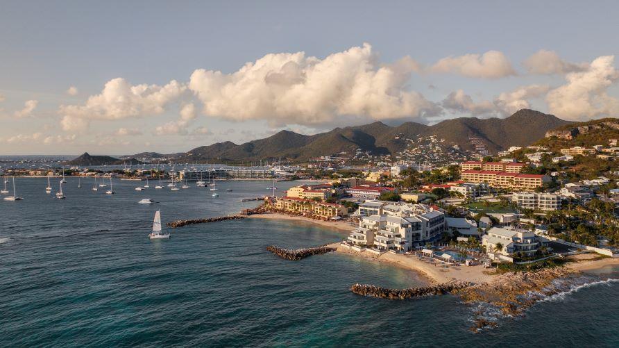 Stunning aerial, sail boat dotted bay, Hilton Grand Vacations resort atop cliff, overlooking blue waters, Sint Maarten. 