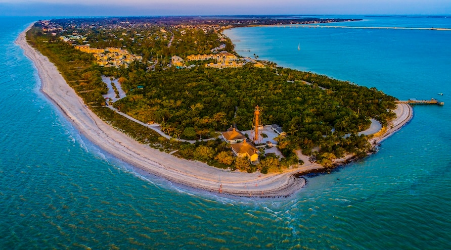 Drone view of Sanibel, Florida at sunset as golden light illuminates buildings and casts a warm glow.