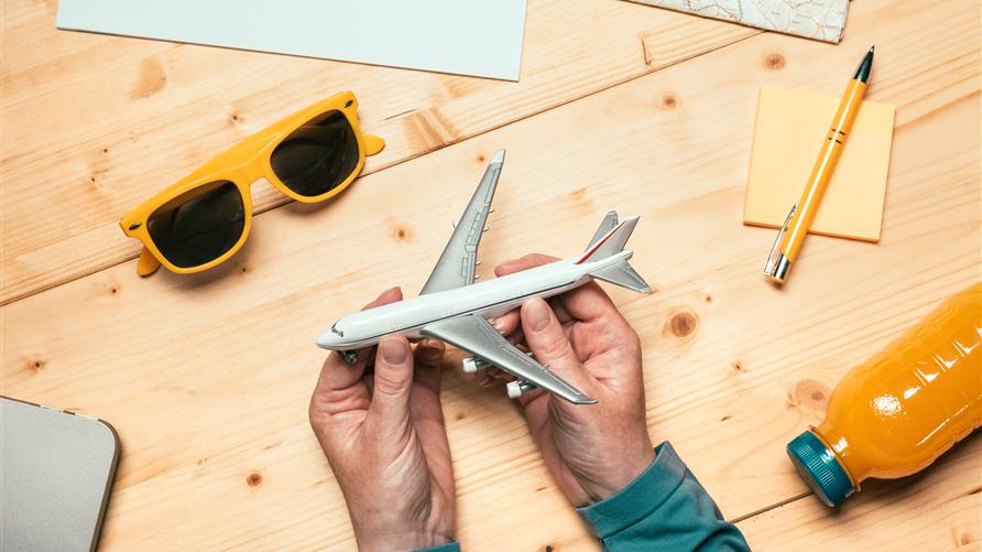 Overhead shot of a man holding a toy airplane with a notepad and pencil nearby.