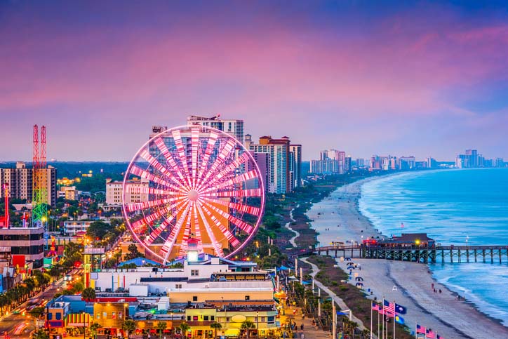 Aerial shot of Myrtle Beach Boardwalk & Promenade and Sky Wheel lighting up with night sky in South Carolina. 
