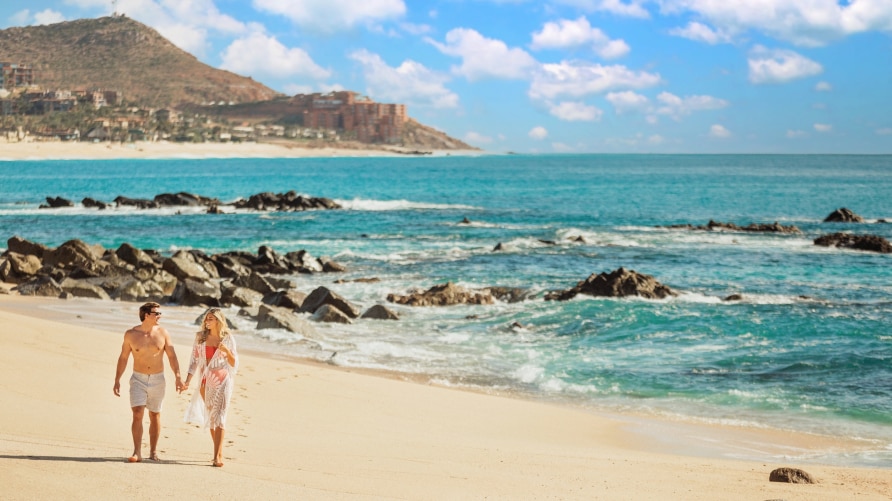 Couple walking along the sunny beach
