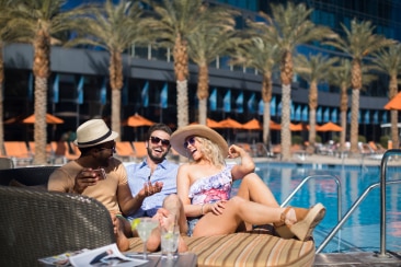 Two men and a woman by the swimming pool laughing together