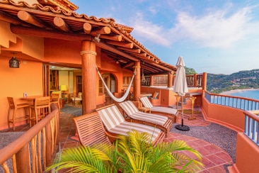 Large balcony off of a resort built of Arizona red rock, sun reclining chairs overlooking a lake