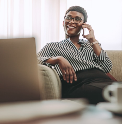Woman sitting on a sofa holding her phone to her ear