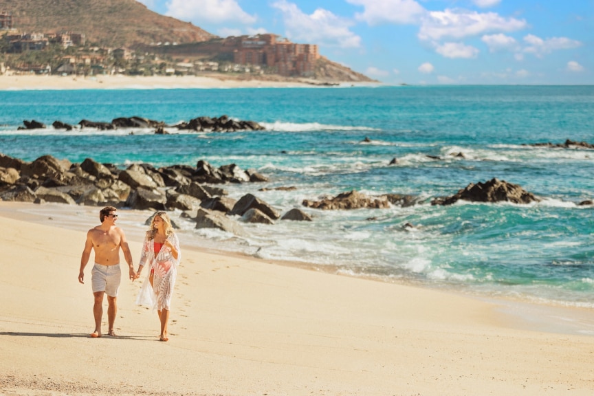 Couple walking along the beach, by the blue ocean