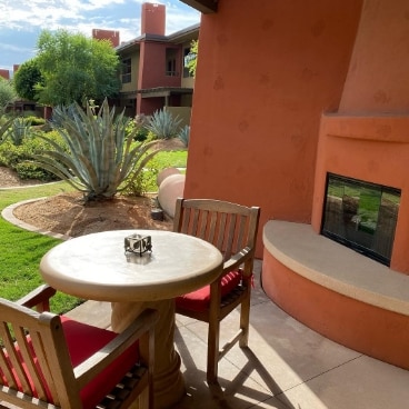 A small dining table for two sits in front of an outdoor fireplace on at terrace at Hilton Grand Vacations Club Palm Desert