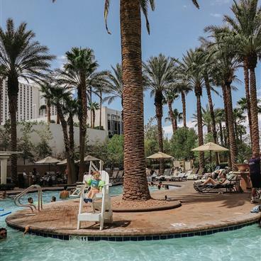 Kids and families enjoy the pool and beach chairs on a sunny day.