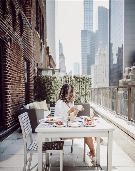 Woman eating lunch on a balcony in New York City.