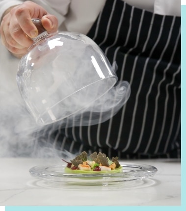 Chef uncovering a plated dinner