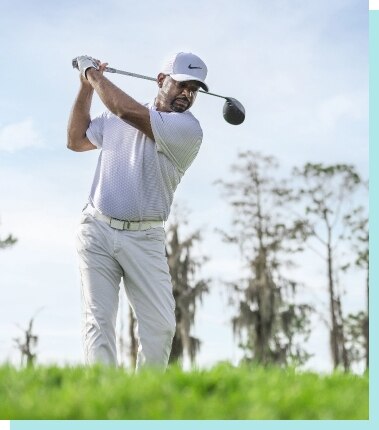 Man hitting a golf ball on the green.