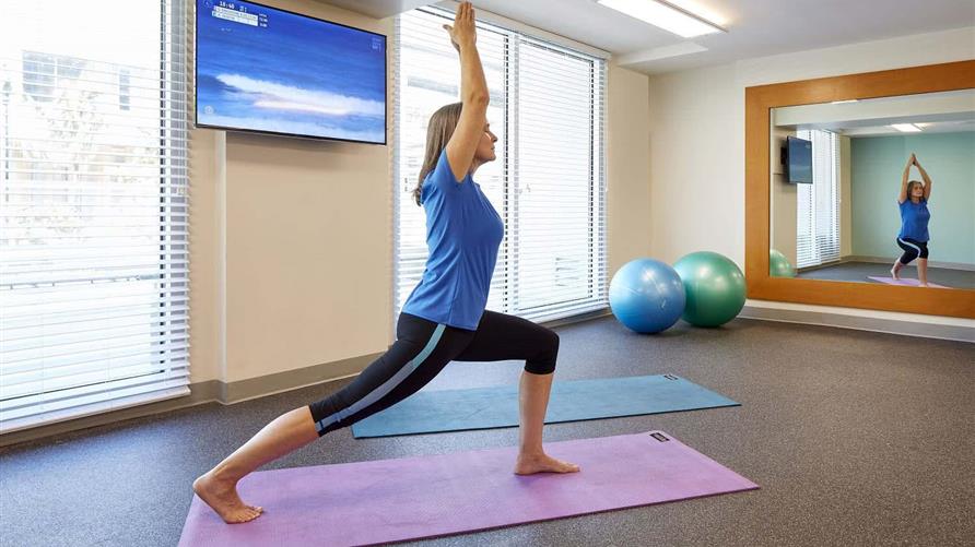 Woman staying healthy on vacation by doing yoga in a Hilton Grand Vacations fitness center. 